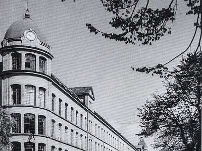 003  Neue Baumwollspinnerei und Vogtländische Baumwollspinnerei Die "Neue Baumwollspinnerei" war nach dem Krieg eine der beiden größten Hofer Textilfabriken. Ihr imposantes Gebäude wurde nach einen vernichtenden Brand am 8. April 1878 im zeitgenössischen Stil repräsentativer Industriebauten errichtet. Im Jahr 1953 feierten sie öffentlichkeitswirksam das 100-jährige Jubiläum ihres Bestehens.  Quelle: Buch "Hof Bewegte Zeiten - Die 50er Jahre"
